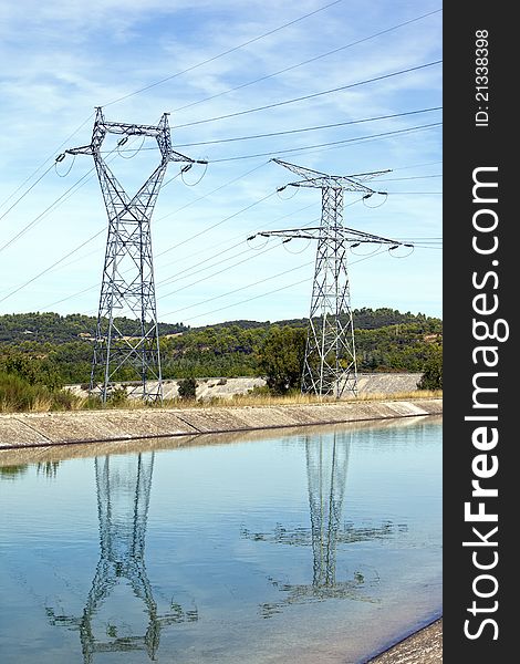 Large power lines reflecting over calm water. Large power lines reflecting over calm water