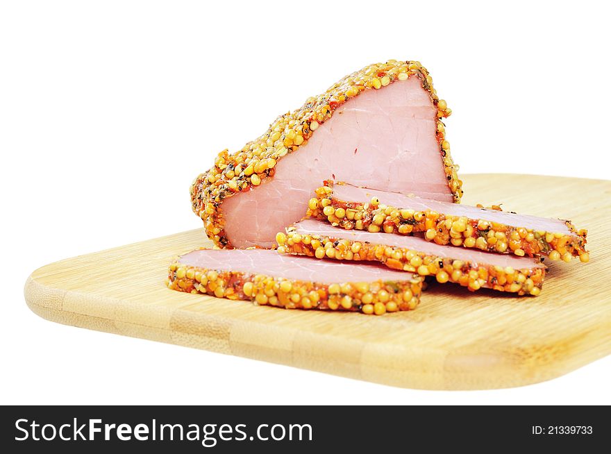 Piece of a ham with spices on a wooden board. Onwhite background.