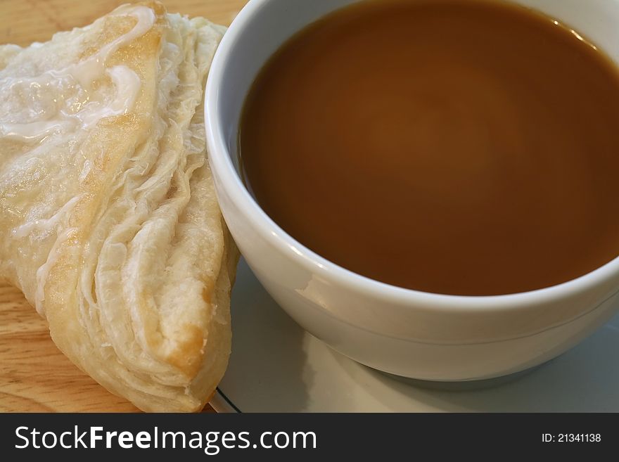 Cup of hot coffee and a fresh backed pastry for breakfast. Cup of hot coffee and a fresh backed pastry for breakfast