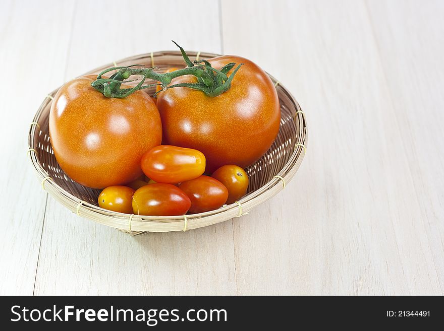 Raw fresh tomatoes in wicker basket on table