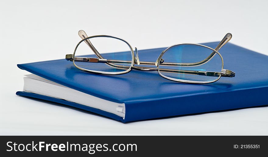 Eyeglasses on a closed notebook on white background. Eyeglasses on a closed notebook on white background