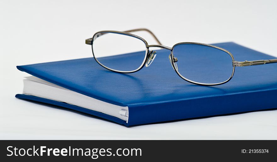 Eyeglasses on a closed notebook on white background. Eyeglasses on a closed notebook on white background