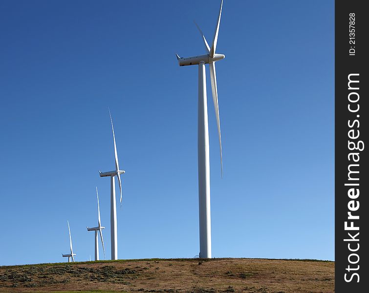 Wind turbines spinning on top of a hill generating power. Wind turbines spinning on top of a hill generating power.