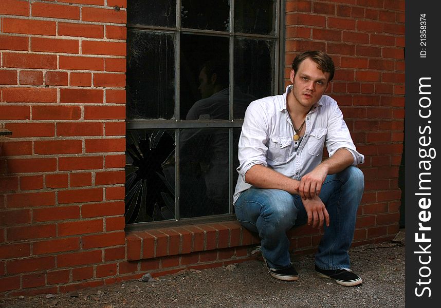 A man sitting on a ledge of a window. A man sitting on a ledge of a window