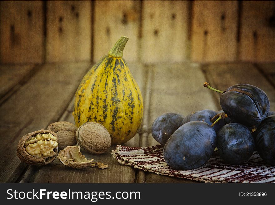 Squash, plums and nuts on an old wood- still life. Squash, plums and nuts on an old wood- still life