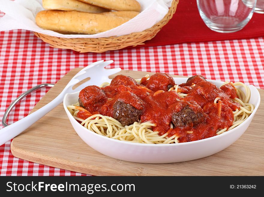 Spaghetti and meat balls in a serving bowl with bread sticks. Spaghetti and meat balls in a serving bowl with bread sticks
