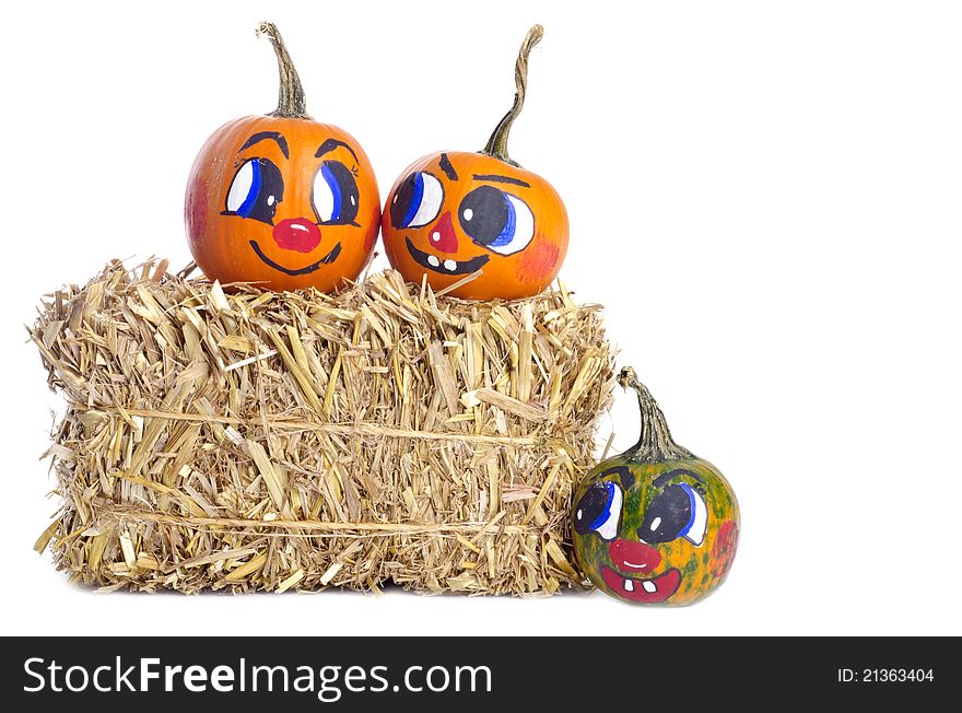 Small pumpkins with painted faces, and a bundle of hay, on white background. Small pumpkins with painted faces, and a bundle of hay, on white background.