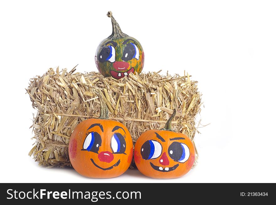 Small pumpkins with painted faces, and a bundle of hay, on white background. Small pumpkins with painted faces, and a bundle of hay, on white background.