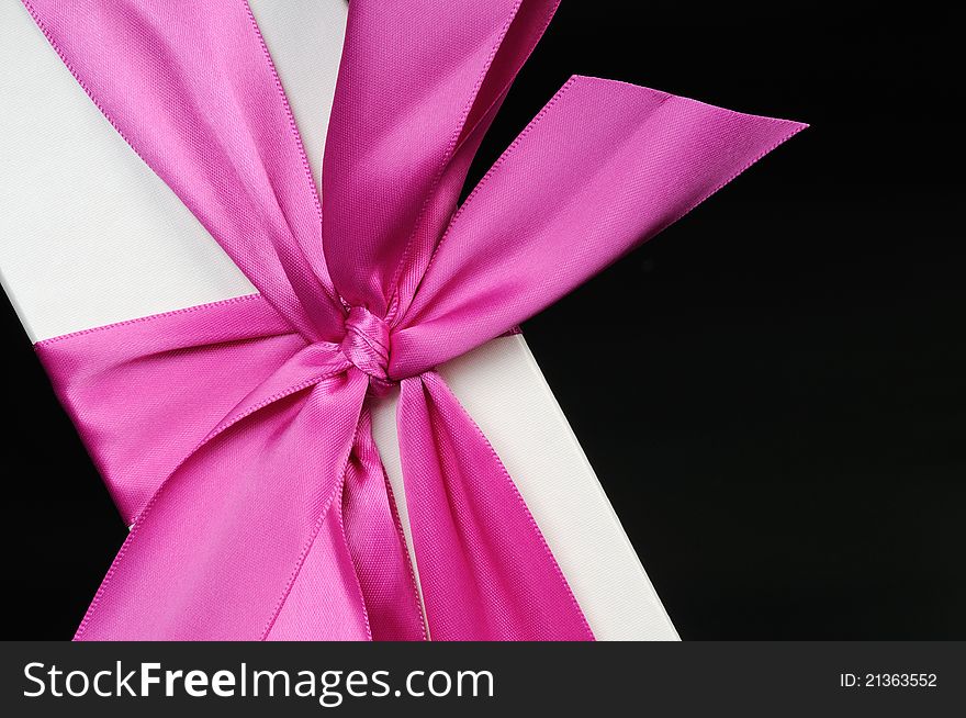 Gift box with a big pink bow close up. On a dark background. Gift box with a big pink bow close up. On a dark background.