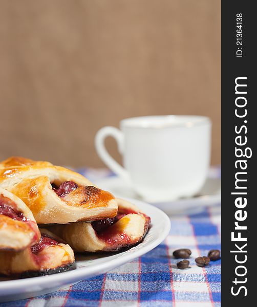 Cherry bun on a plate and cup of coffee