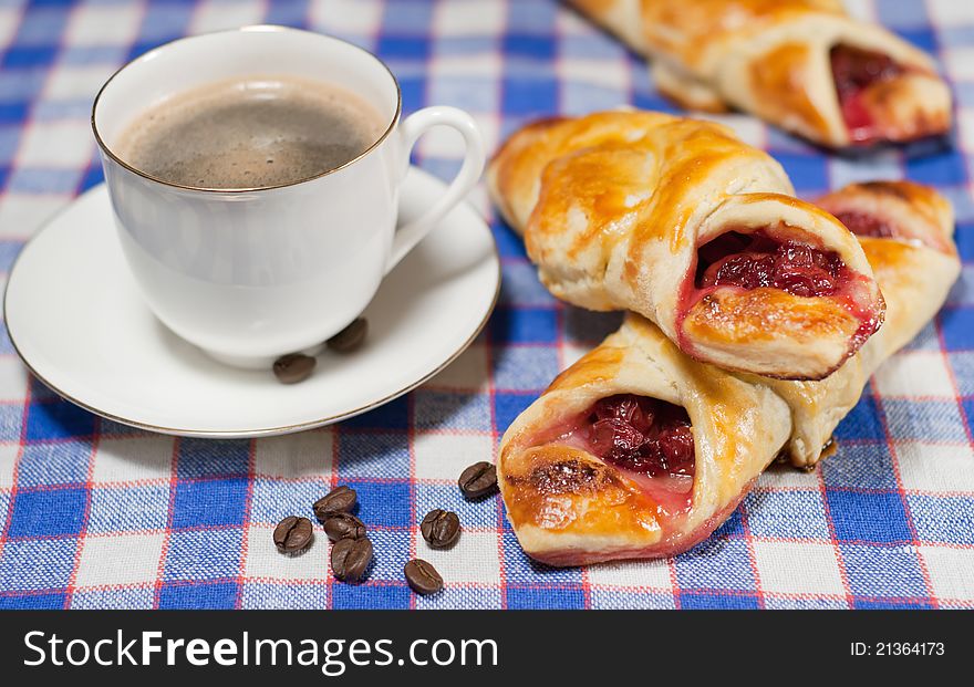 Cherry bun on a plate and cup of coffee