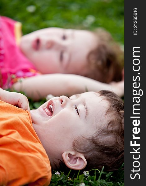 A smiling boy and a little girl are lying on the grass. A smiling boy and a little girl are lying on the grass