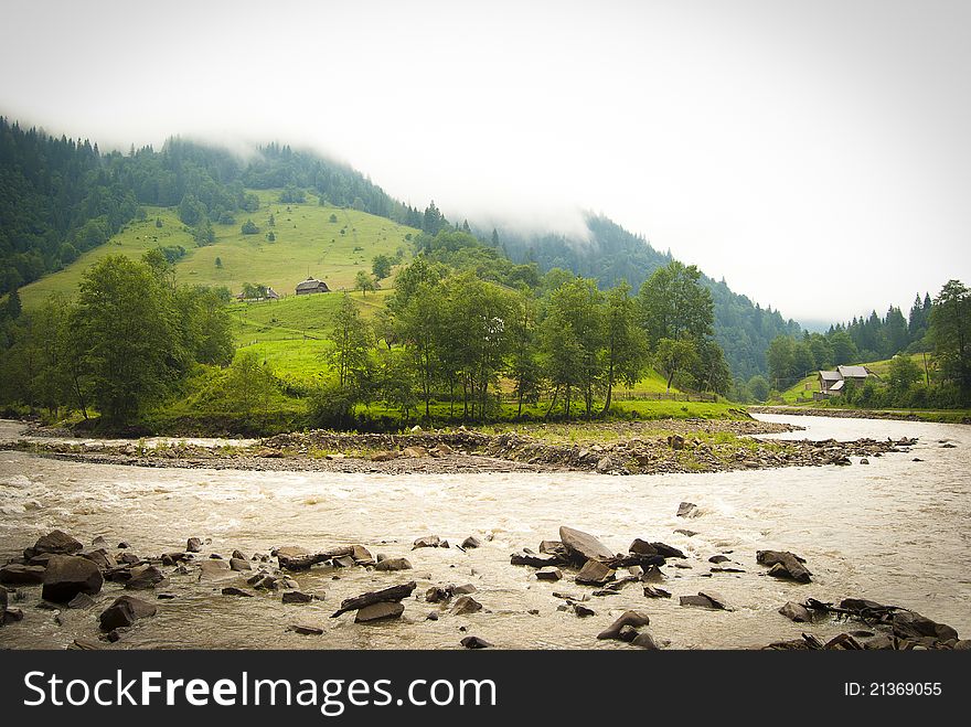 A mountain landscape view on a tiny village with wooden huts and a mountain river in the Ukrainian Carpathian mountains. A mountain landscape view on a tiny village with wooden huts and a mountain river in the Ukrainian Carpathian mountains