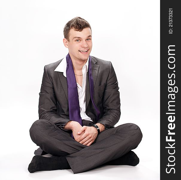 Relaxed young business man sitting on the floor over white background