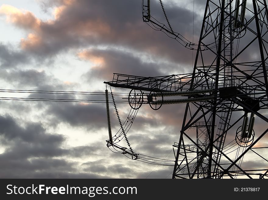 High voltage power pylons on against sunset sky