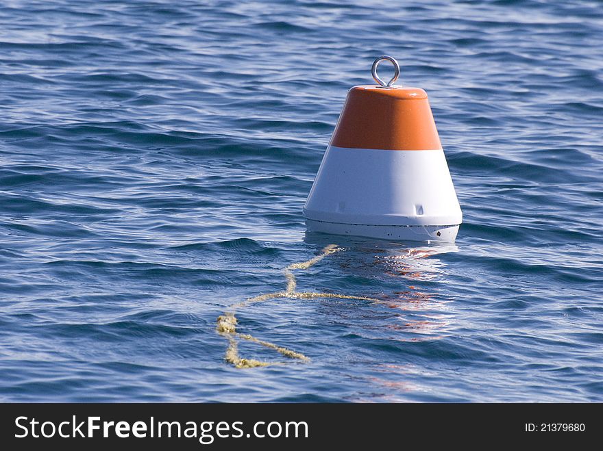 Red and white buoy bobbing in blue water