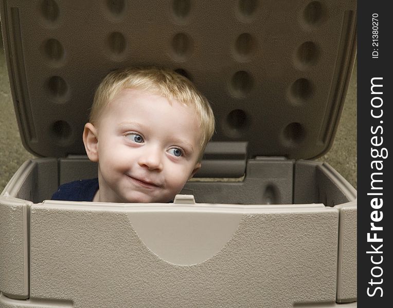 Little boy playing in a storage box with a cute expression on his face. Little boy playing in a storage box with a cute expression on his face