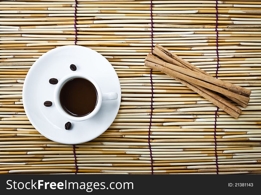 Coffee in cup and cinnamon on burlap of bamboo