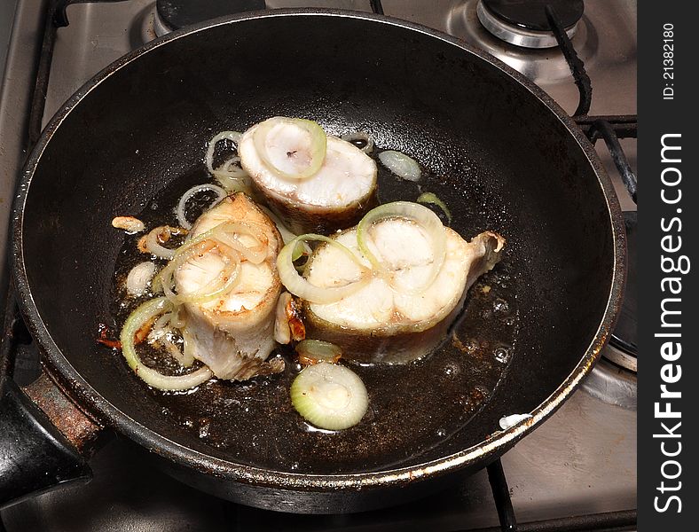 White fish is fried on a frying pan. White fish is fried on a frying pan