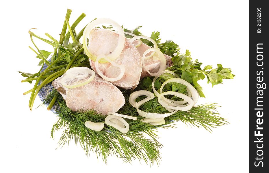 Pieces of white fish, onions, grass lie on a plate. Pieces of white fish, onions, grass lie on a plate