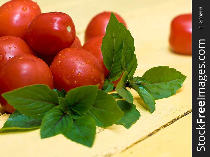 Pile of tomatos and basil leaves on wooden table
