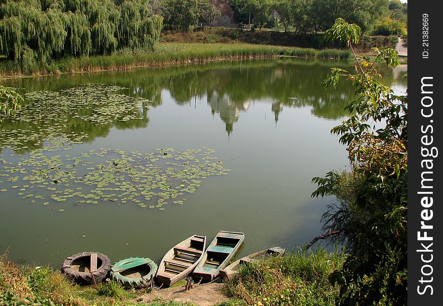 Reflection of the temple on the surface of the water. Near the lake's bank are wooden boats.