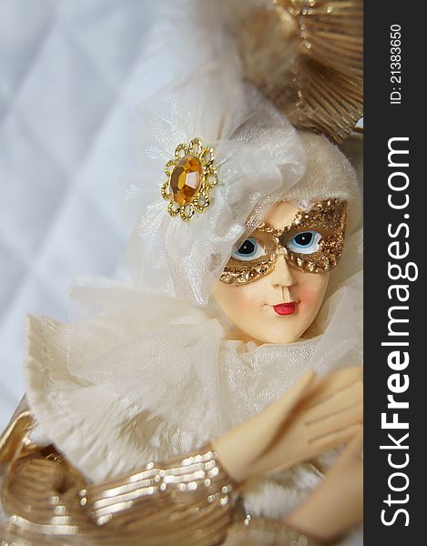 Arlekino porcelain doll on background of the white quilted fabrics. Arlekino porcelain doll on background of the white quilted fabrics