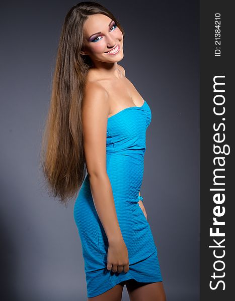 Beautiful professionally madeup smiling sexy girl with long brown hair wearing blue dress. Beautiful professionally madeup smiling sexy girl with long brown hair wearing blue dress