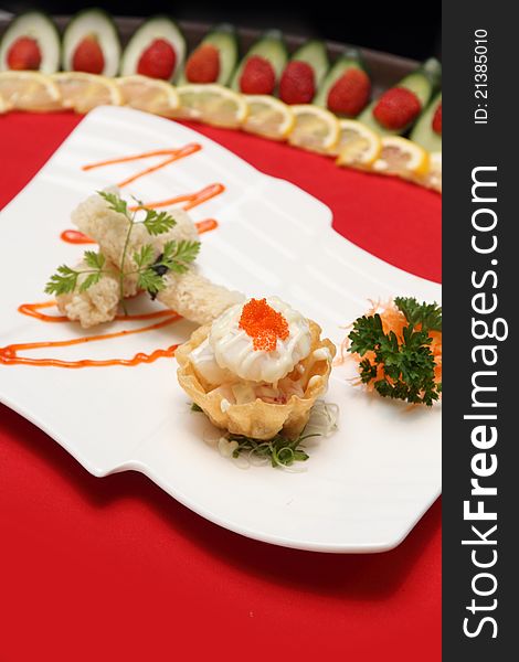 A plate of mixed Chinese delicacies, placed on a white plate and having also soup and sauces on the background.