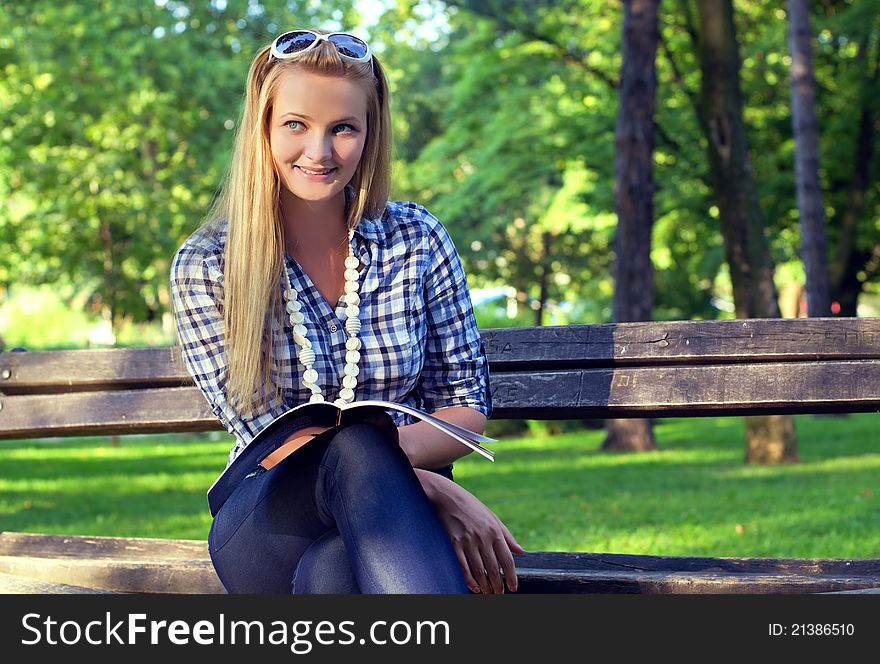 Young woman reading book in a park. Young woman reading book in a park