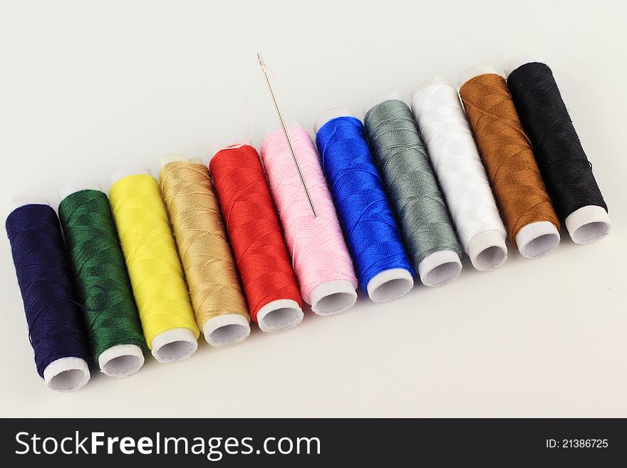 The color threads and needle  by oblique pattern with isolated white background. The color threads and needle  by oblique pattern with isolated white background
