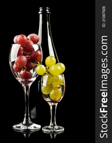 Grapes in a glass and a bottle of wine isolated on a black background
