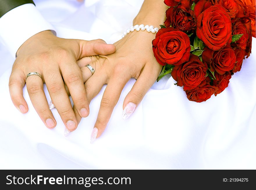 Bride and groom holding hands and a bouquet of red roses. Bride and groom holding hands and a bouquet of red roses