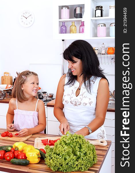 Mother and daughter in the kitchen preparing the salad. Mother and daughter in the kitchen preparing the salad