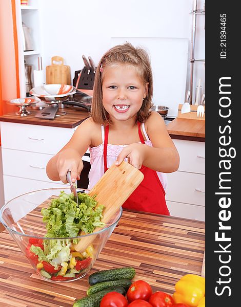 Smiling young girl making a fresh salad in the kitchen. Smiling young girl making a fresh salad in the kitchen