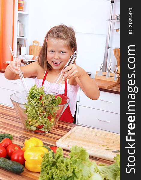 Smiling young girl making healthy salad in the kitchen. Smiling young girl making healthy salad in the kitchen