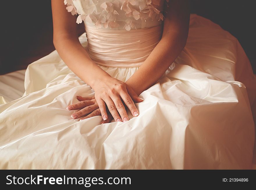 Woman in a wedding dress holding hands on the knees. Woman in a wedding dress holding hands on the knees