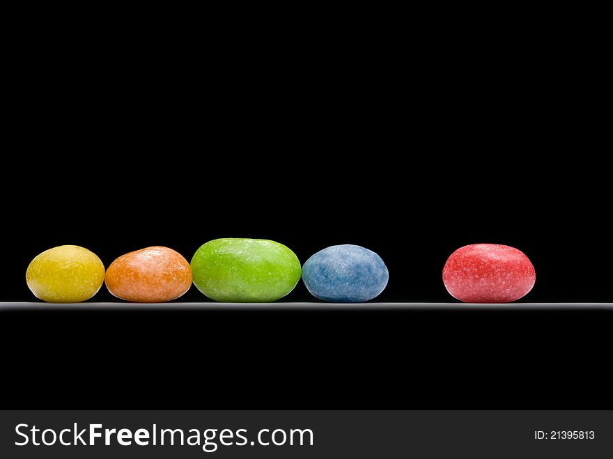 Multi-coloured sweets (five pieces) on a black background. Multi-coloured sweets (five pieces) on a black background.