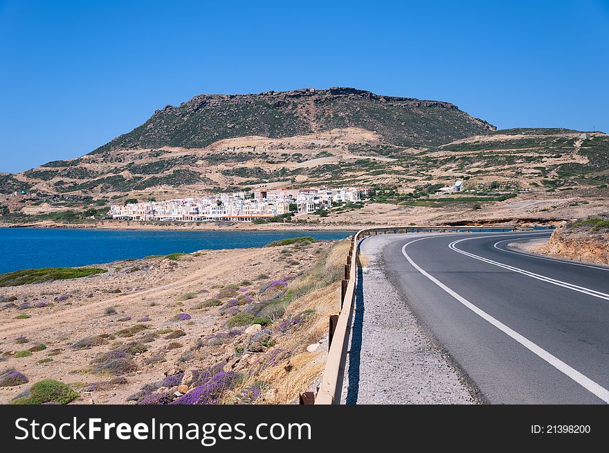 Typical landscape of Crete. The road leading to the city in Crete, blue sea and white houses. Typical landscape of Crete. The road leading to the city in Crete, blue sea and white houses