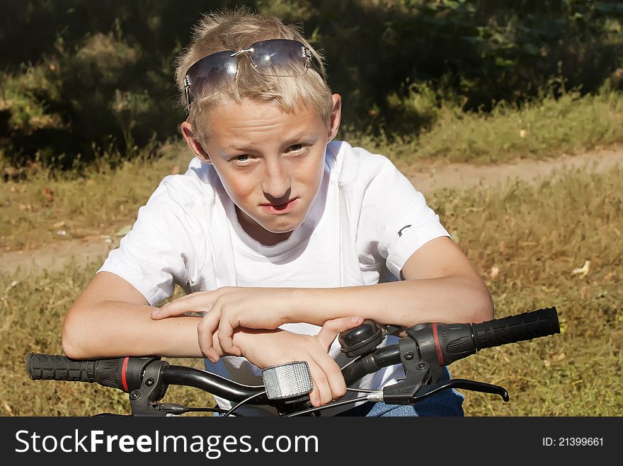 Portrait of a teenage boy on a bicycle in summer park outdoors