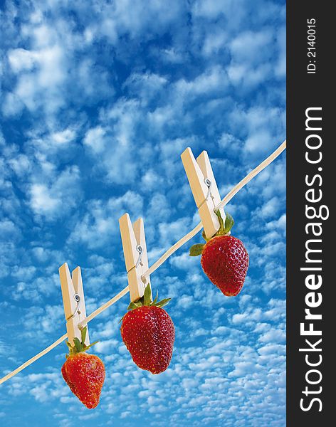 Three strawberry's hanging to dry and a cloudy sky. Three strawberry's hanging to dry and a cloudy sky