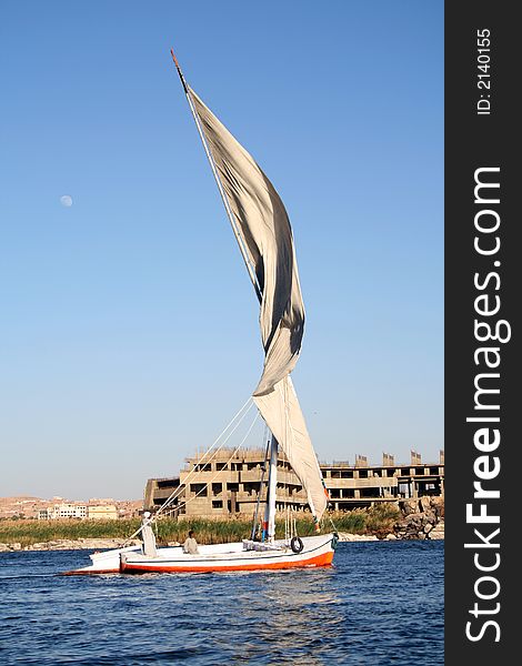 Traditional Egyptian Felucca sailing boat in river nile in Aswan southern Egypt... The moon is in the sky on the left hand side...