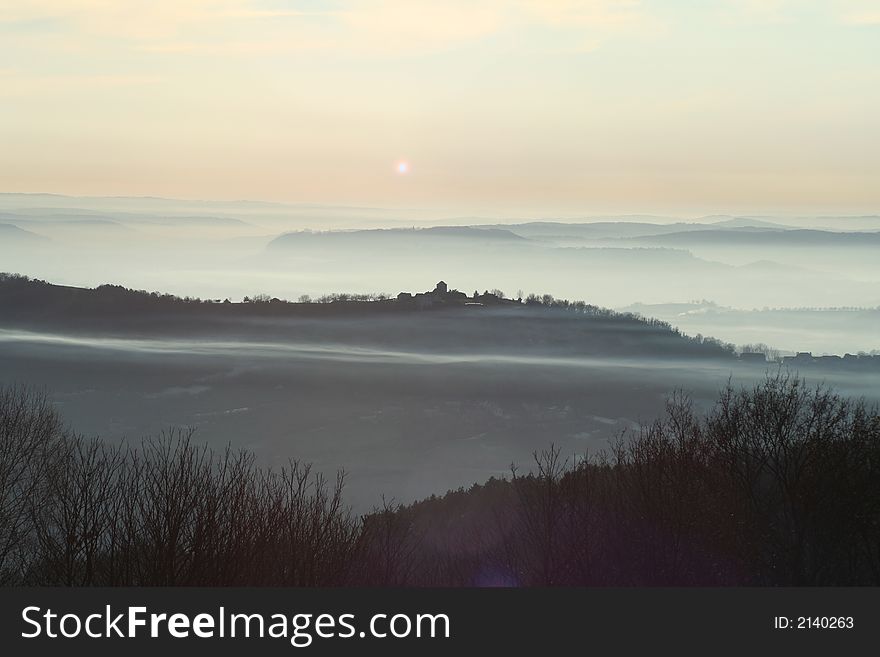 Streak of mist going through village at sunset