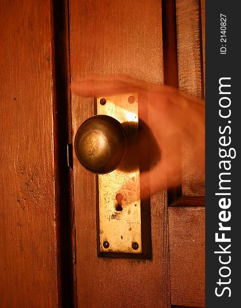 Blurred hand reaching for a vintage door knob on an old door. Blurred hand reaching for a vintage door knob on an old door