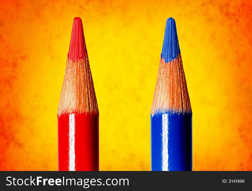 Two coloring pencils over a vibrant, lightly textured background