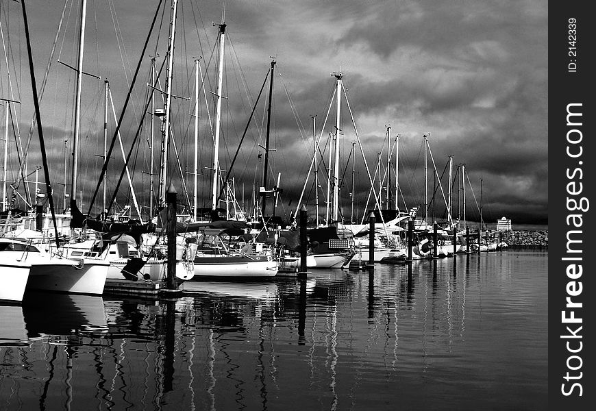 Sailboats in their stalls at marina behind the breakwater  as storm approaches. Sailboats in their stalls at marina behind the breakwater  as storm approaches