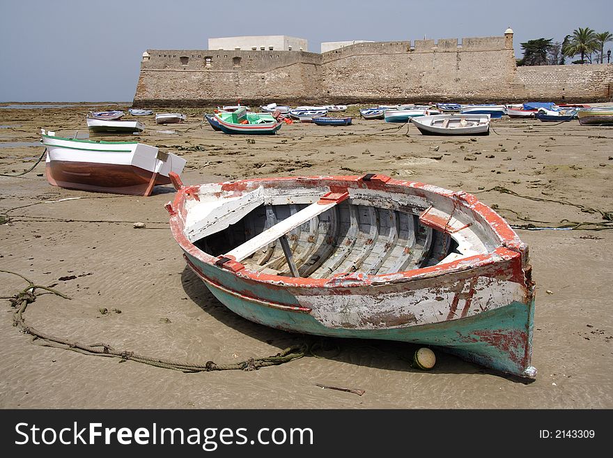 Small fishing boats while low tide on the ocean bed with an old castle in the background. Small fishing boats while low tide on the ocean bed with an old castle in the background