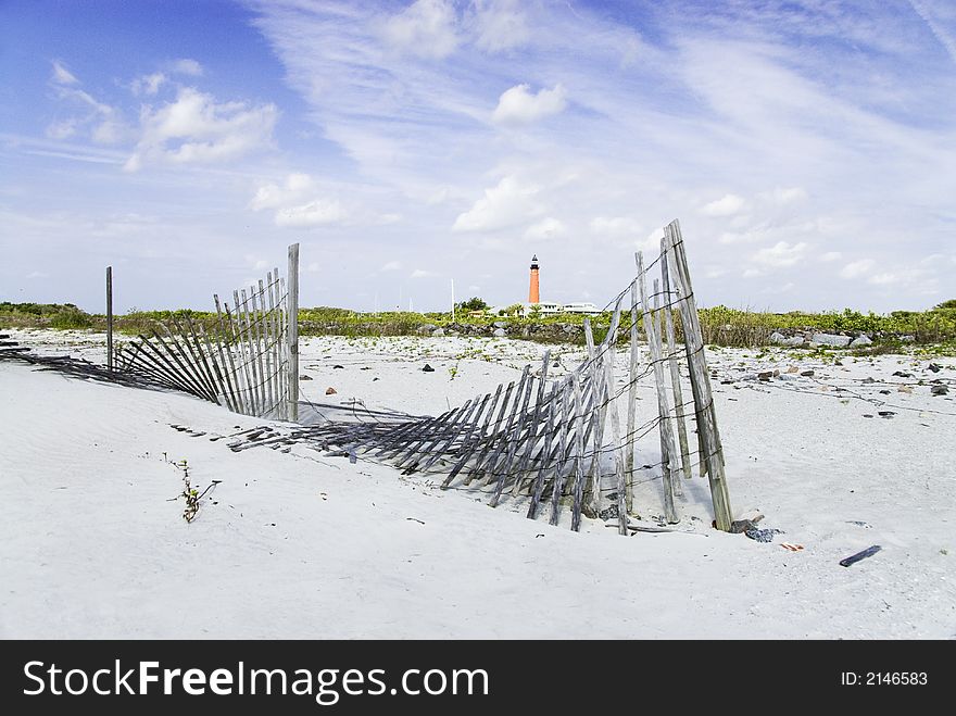 A weathered and fallen sand fence tries to hold the dunes back on this coastal beach. A weathered and fallen sand fence tries to hold the dunes back on this coastal beach