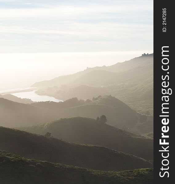 A view of pacific ocean over green hills during sunset. A view of pacific ocean over green hills during sunset