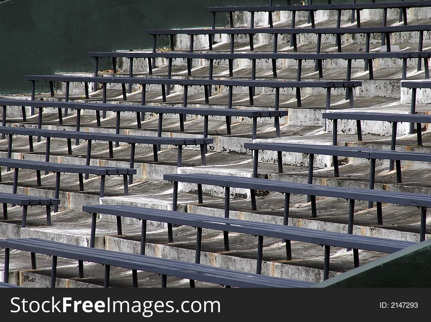 Blue Benches On A Grey Concrete Ground In Rows, Stadium Seats. Blue Benches On A Grey Concrete Ground In Rows, Stadium Seats